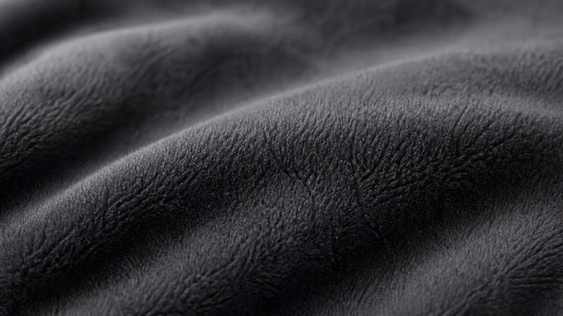 Vue macro de la texture douce en flanelle utilisée pour une couverture lestée anthracite.