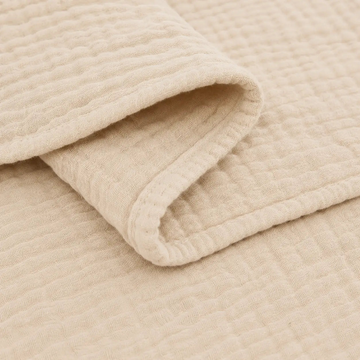 Couverture d’été Amaya beige, légère et respirante, avec détail de la bordure et du tissu gaufré en coton.