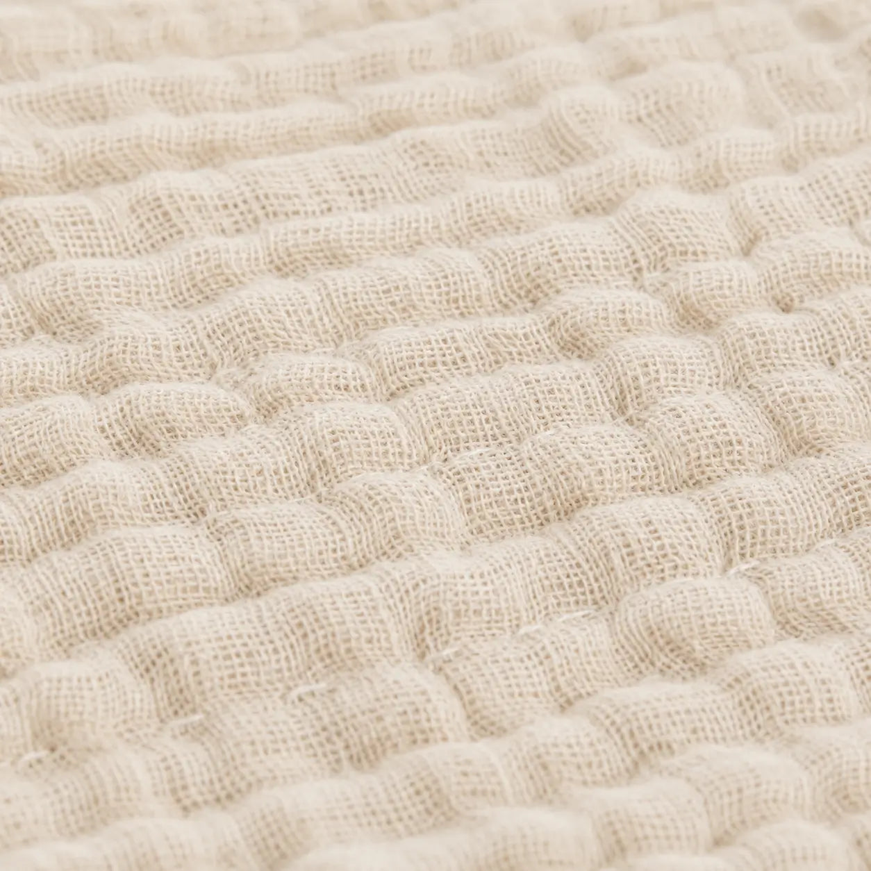 Couverture d’été Amaya beige, légère et respirante, avec détail du tissu gaufré en gros plan.