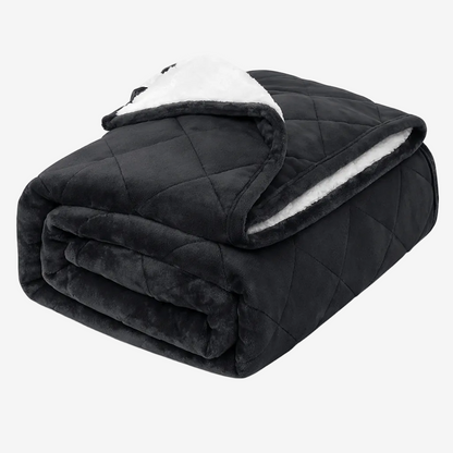 Couverture lestée noire pliée avec face en flanelle et doublure sherpa blanche sur fond blanc.