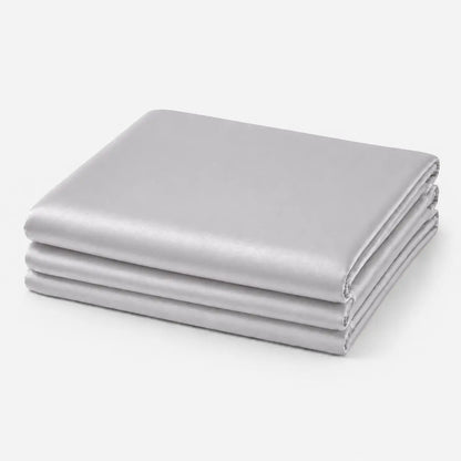Couverture rafraîchissante en coloris gris perle, pliée sur fond clair, avec une finition soie glacée douce et légèrement satinée.