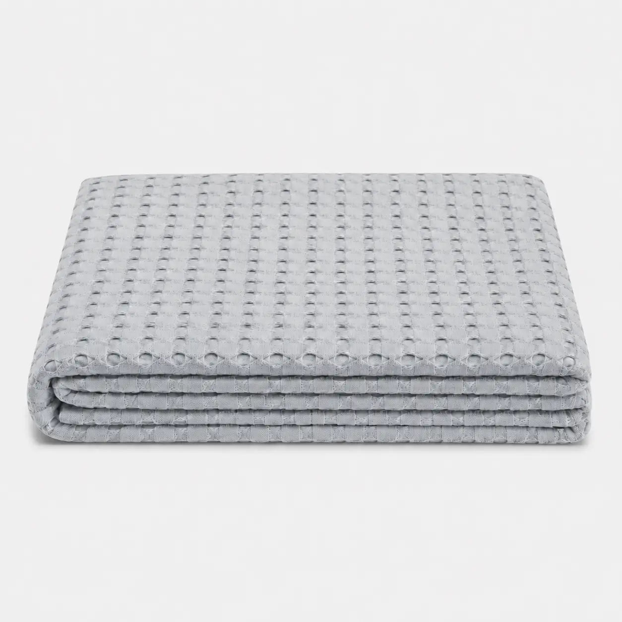 Couverture rafraîchissante Nuvia en fibre de bambou gris perle, pliée sur fond clair avec texture gaufrée respirante et toucher doux.
