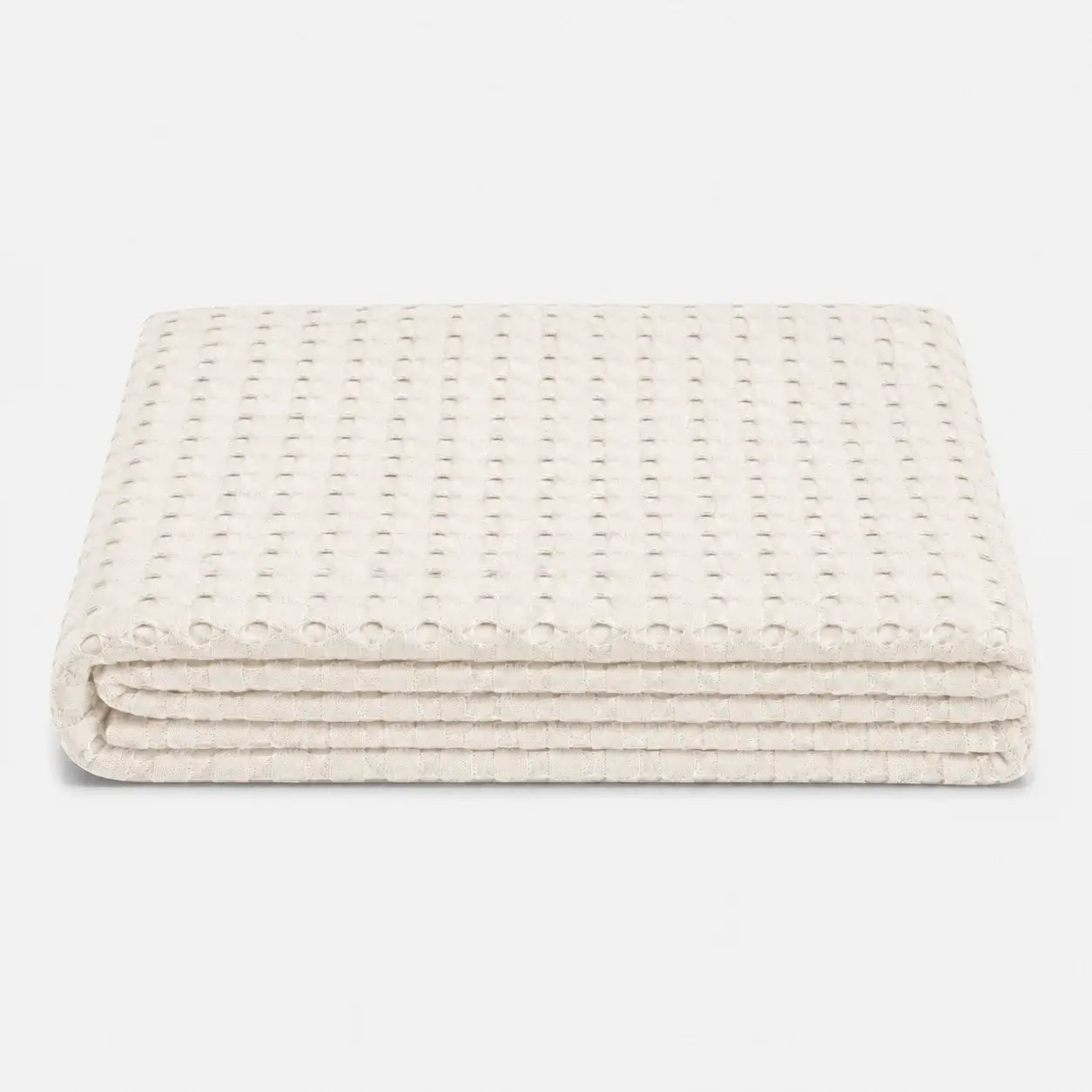 Couverture rafraîchissante Nuvia en fibre de bambou ivoire, pliée sur fond clair avec texture gaufrée respirante et finition douce.
