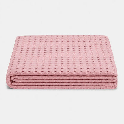 Couverture rafraîchissante Nuvia en fibre de bambou rose poudré, pliée sur fond clair avec texture gaufrée respirante et toucher doux.