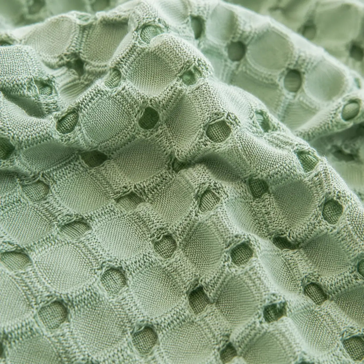 Gros plan sur la texture gaufrée respirante de la couverture rafraîchissante Nuvia en fibre de bambou vert sauge.
