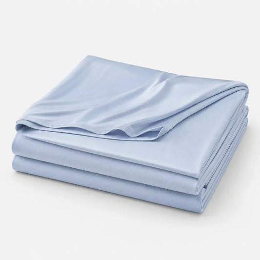 Couverture rafraîchissante Marea bleu poudré, légère et respirante, en tissu effet soie glacée, présentée pliée sur fond blanc.