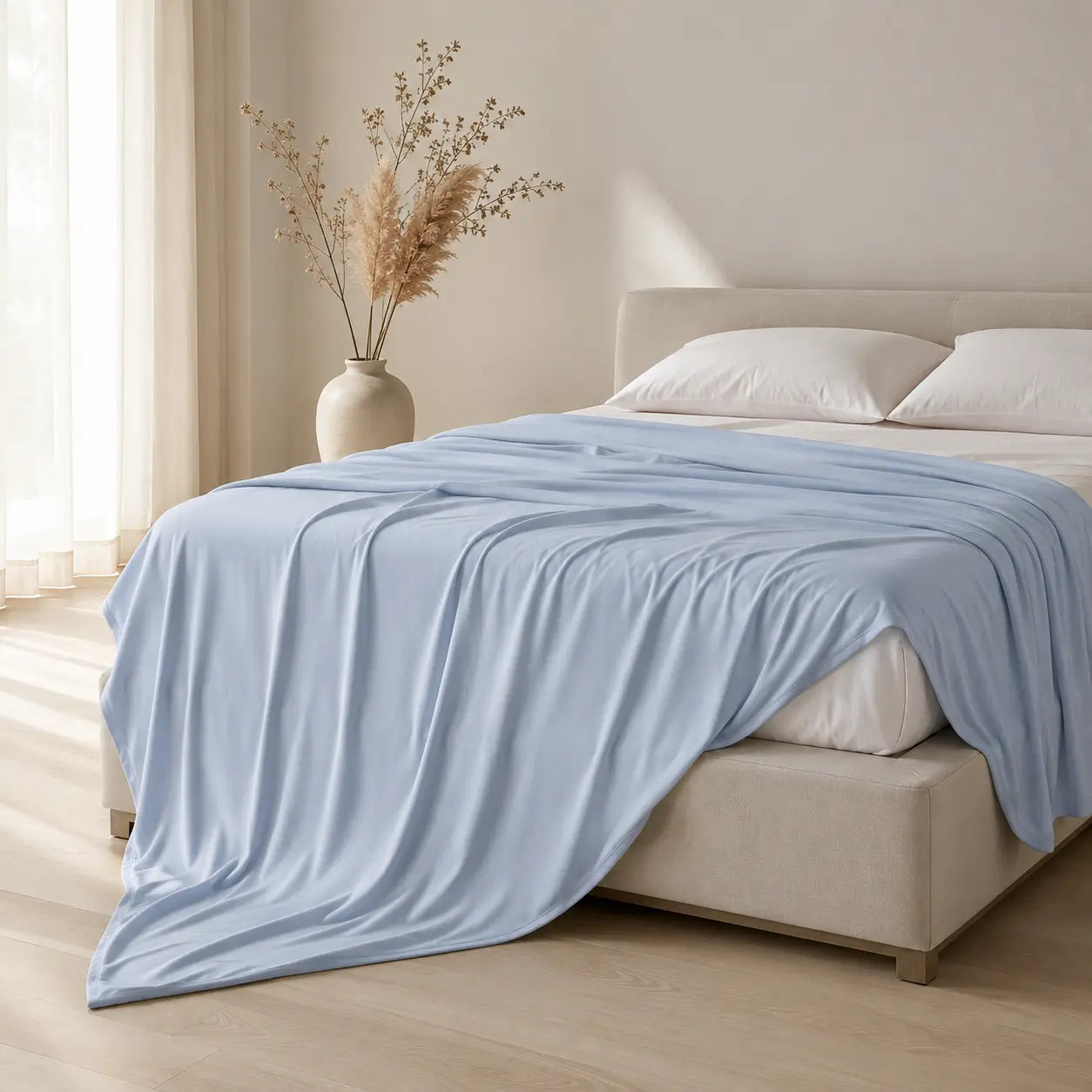 Couverture rafraîchissante Marea bleu poudré drapée sur un lit dans une chambre lumineuse au style Japandi, avec une ambiance douce et apaisante.