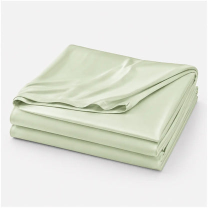 Couverture rafraîchissante Marea vert sauge, légère et respirante, en tissu effet soie glacée, présentée pliée sur fond blanc.