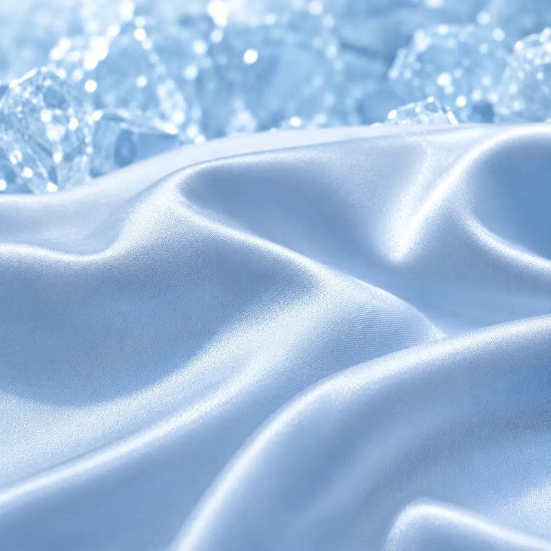 Gros plan sur le tissu rafraîchissant Marea bleu poudré avec un effet de fraîcheur inspiré de la glace, mettant en valeur sa surface douce, fluide et respirante pour les nuits d'été.