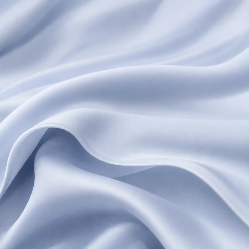 Gros plan sur le tissu de la couverture rafraîchissante Marea bleu poudré, mettant en valeur son tombé fluide, sa douceur et sa légèreté pour un confort optimal pendant les nuits chaudes.